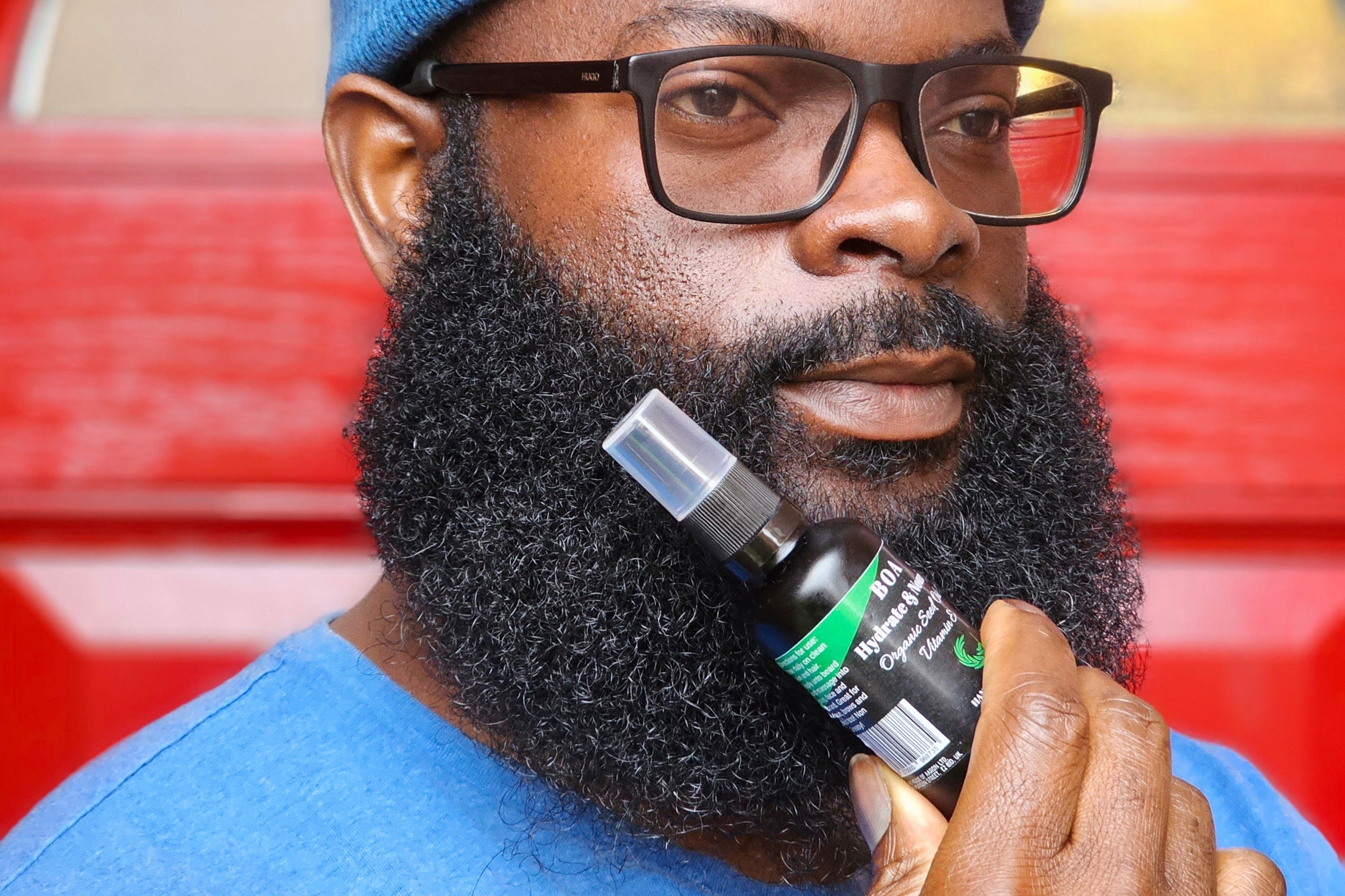 Man holding a bottle of beard oil with a red background